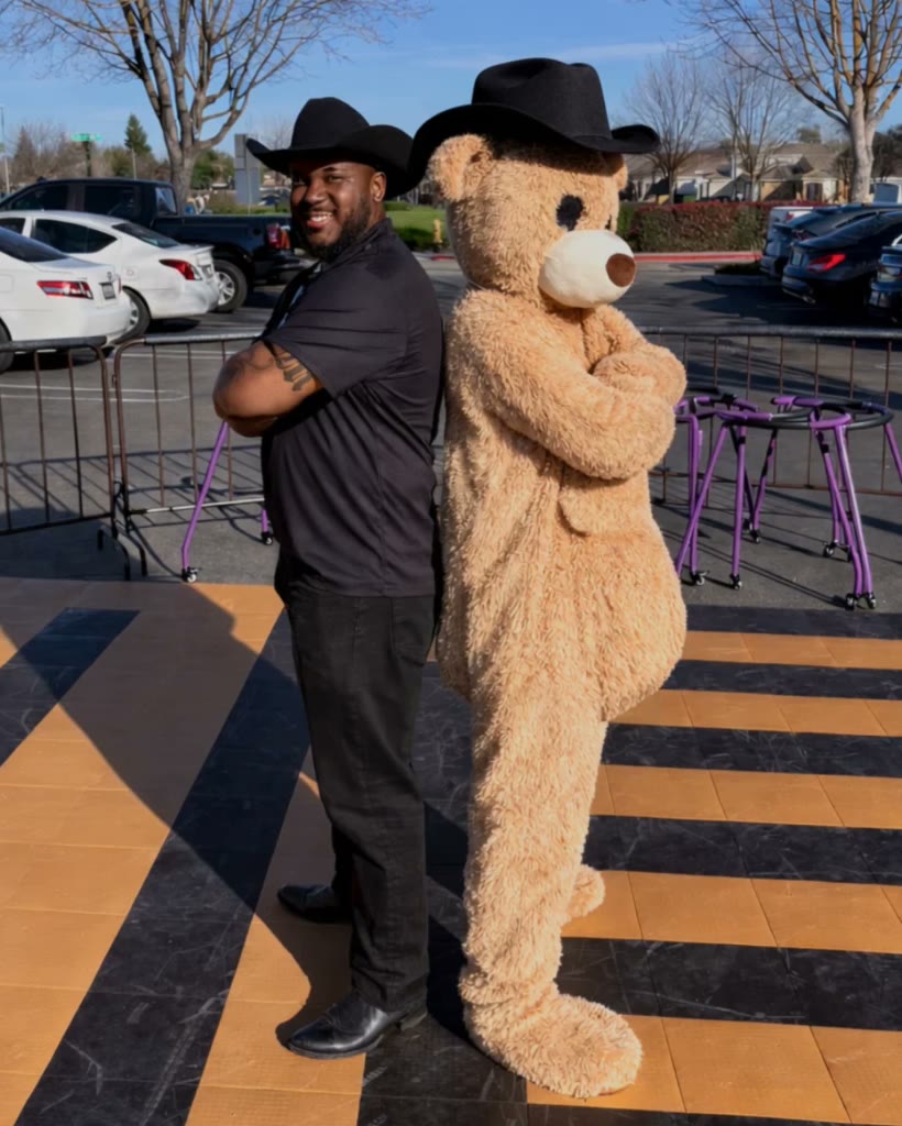 Roll W. Me founder in a cowboy hat standing back to back with the teddy bear mascot on the rink